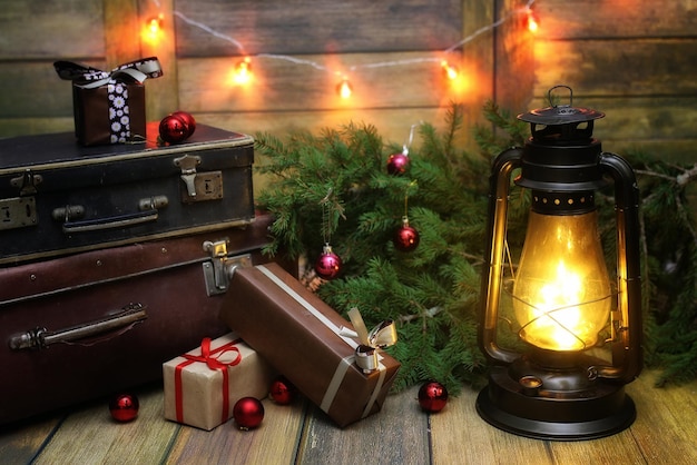 Composizione di Capodanno di rami di alberi di Natale decorati con palline Lampada vintage con candele accese e scatole piene di regali