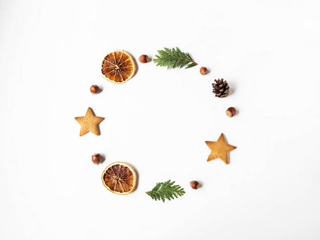 Composizione di cornice cerchio di Natale piatto laico - biscotto a stella, noci, fette d'arancia secche, pigna e rami di abete. vista dall'alto, copia spazio