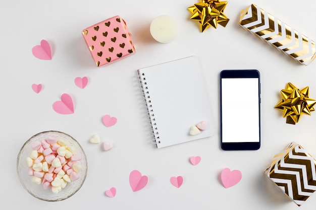 Composizione di cuori rosa di carta, regali, un telefono e marshmallow a forma di cuore