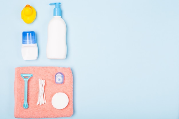 Composizione di disposizione piana sistemata di vista superiore di mattina di cura del corpo del fronte del bagno della donna con gli oggetti bianchi e blu sullo scrittorio blu-chiaro