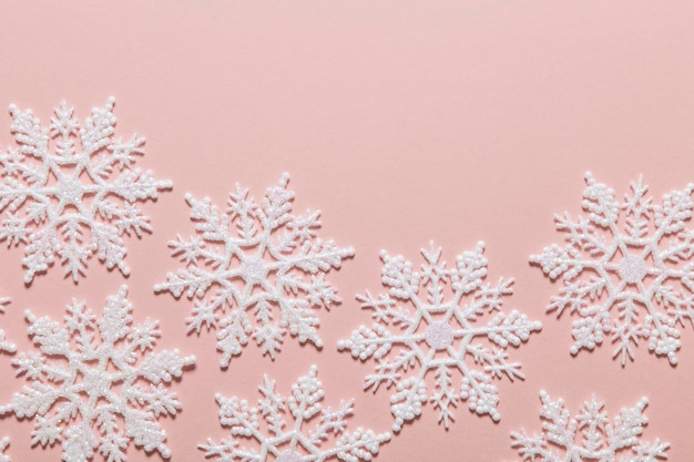 Composizione di fiocchi di neve glitterati bianchi su sfondo rosa pastello