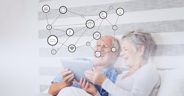 Composizione di icone digitali su una coppia anziana felice che utilizza tablet a letto
