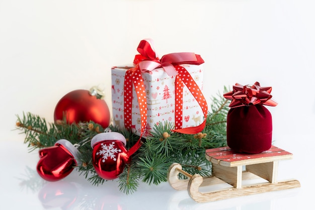 Composizione di Natale con decorazioni, palline, scatole regalo, guanti e slitta di Babbo Natale su bianco. Vacanze di Natale con copyspace.