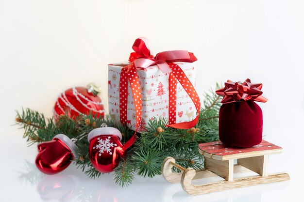 Composizione di Natale con decorazioni, palline, scatole regalo, guanti e slitta di Babbo Natale su bianco