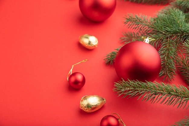 Composizione di Natale. Decorazioni, palline rosse, rami di abete e abete rosso su carta rossa.