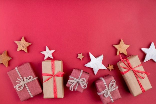 Composizione di natale. Decorazioni, stelle e contenitori di regalo rossi di natale su priorità bassa rossa. Vista piana, vista dall'alto, spazio per il testo