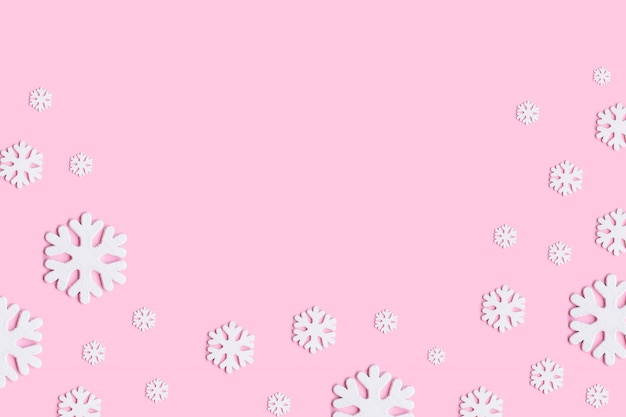 Composizione di Natale di fiocchi di neve su sfondo rosa pastello.