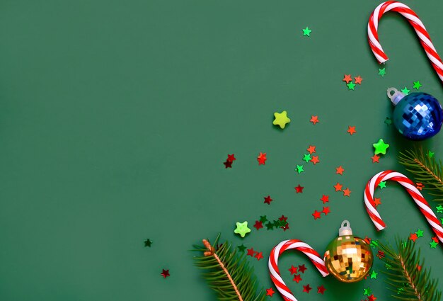 Composizione di Natale di rami di un albero, canne dolci, palle di Natale, stelle su un verde