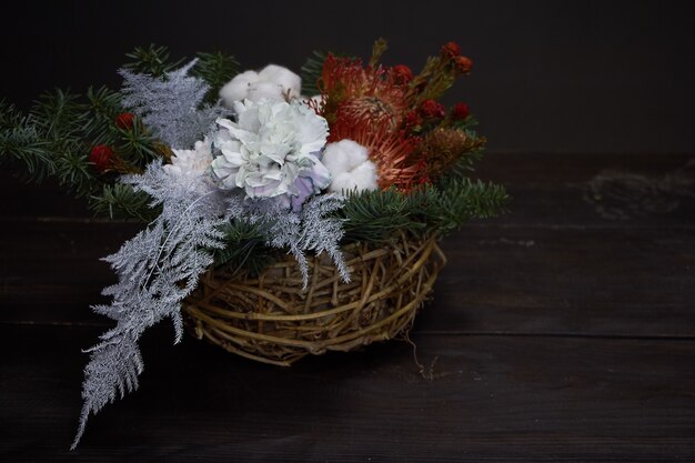 Composizione di Natale e Capodanno. Cestino di vimini con rami di abete decorati con materiali naturali su oscurità