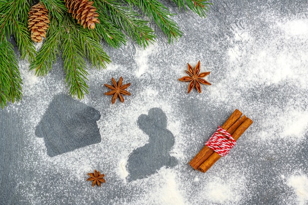 Composizione di natale. Farina silhouette di biscotti tra i rami degli alberi di Natale, coni, anice stellato e cannella.