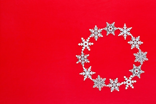 Composizione di Natale. Ghirlanda di fiocchi di neve bianca decorazioni su sfondo rosso. Natale, inverno, concetto di capodanno. Appartamento laico, vista dall'alto, copia.