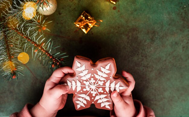 Composizione di Natale. Un albero di Natale decorato con giocattoli e una ghirlanda e pan di zenzero. Pan di zenzero nelle mani di un bambino. Foto di alta qualità