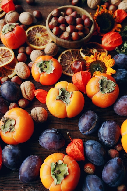 Composizione di natura morta autunnale con frutta e verdura biologica fresca Assortimento di prugne cachi noci girasoli e arance secche fuoco selettivo