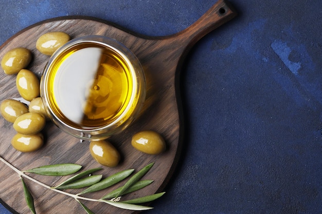 Composizione di olive verdi, olio, spezie su sfondo blu. Spazio per il testo.