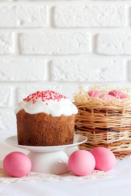 Composizione di Pasqua con cesto di vimini con uova colorate di rosa e torta di Pasqua decorata