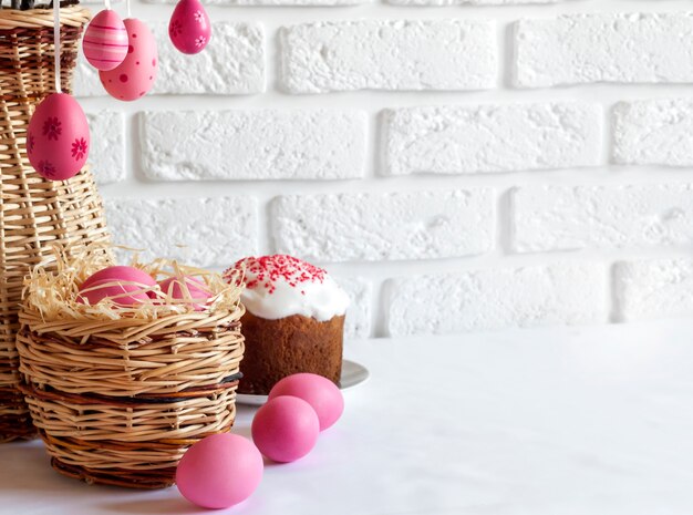 Composizione di Pasqua con le uova colorate rosa in canestro di vimini e dolce di Pasqua