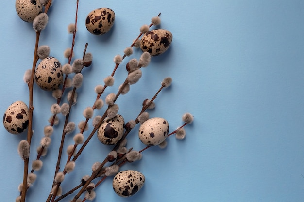 Composizione di Pasqua di uova e rami di alberi con fiori su sfondo blu.