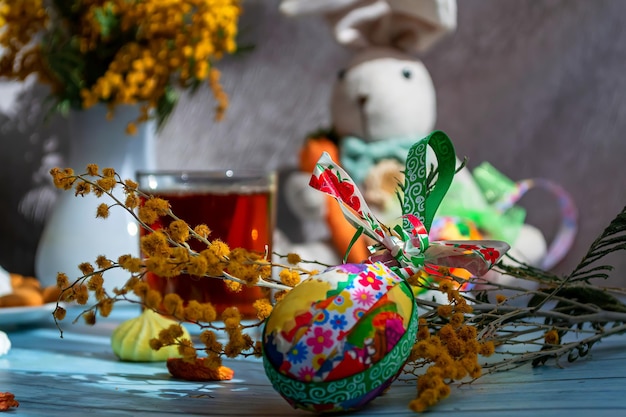 Composizione di Pasqua su uno sfondo di legno blu Simpatico bouquet di mimosa di uova colorate di coniglietto