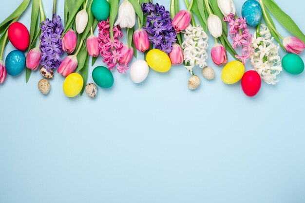 Composizione di Pasqua. Uova di Pasqua multicolori, tulipani e giacinti sul tavolo blu. Concetto di pasqua.