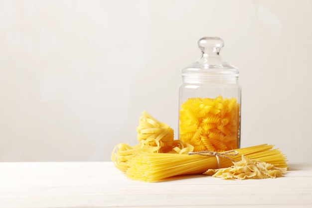 Composizione di pasta diversa cruda con posto per il testo su uno sfondo di legno bianco. Vista dall'alto.