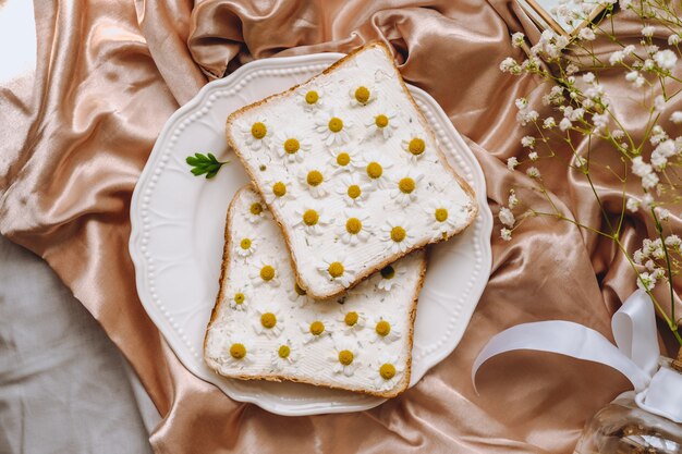 Composizione di primavera, panino di pane tostato con fiori di camomilla in un piatto bianco