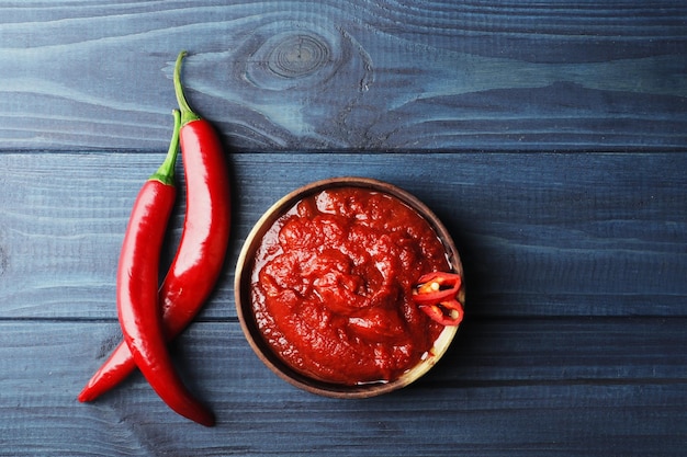 Composizione di salsa di pomodoro calda in una ciotola di legno su fondo di legno blu