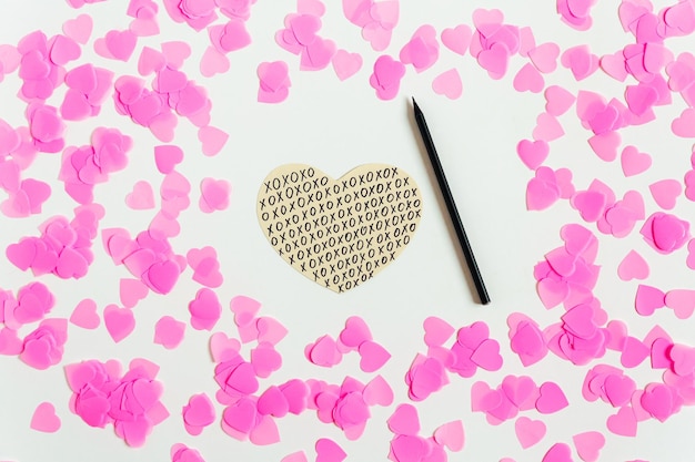 Composizione di San Valentino Sfondo bianco con coriandoli rosa cuore di carta disegnato a mano e matita Vista dall'alto