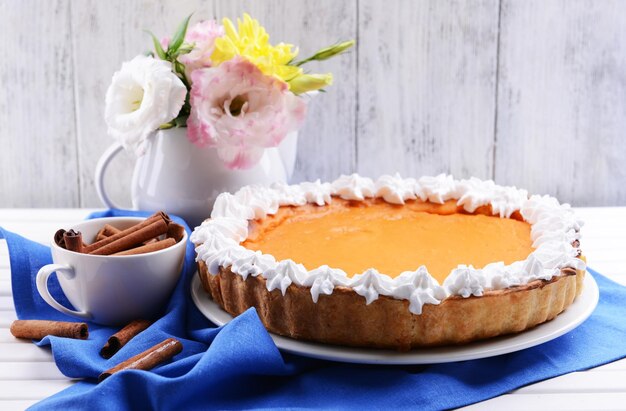 Composizione di torta di zucca fatta in casa su piatto e fiori in vaso su sfondo di legno