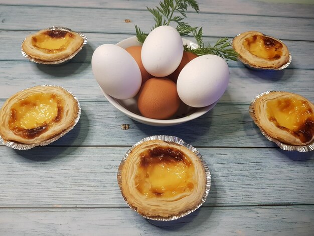 Composizione di torte belem e decorazione con ciotola di uova su legno invecchiato