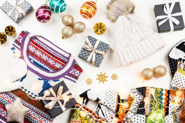 Composizione di umore natalizio con regali e luci di cappello da maglione Concetto invernale disteso piatto