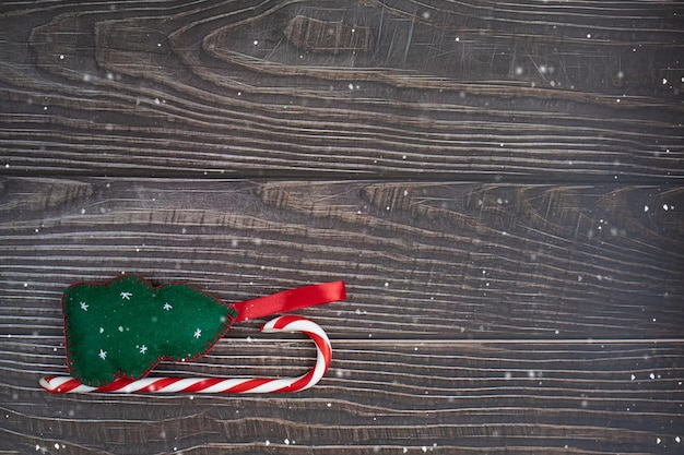 Composizione di un albero di Capodanno e caramelle di Natale. Slitta su uno sfondo di legno scuro con la neve.