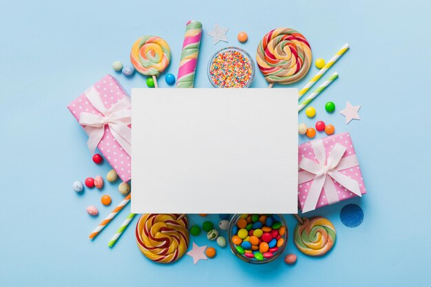 Composizione di vacanza piatta carta vuota lecca-lecca decorazioni di compleanno su sfondo colorato Spazio di copia della vista superiore per il testo