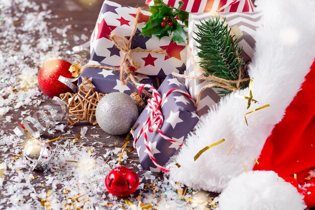 Composizione di vacanze di Natale con cappello rosso di Babbo Natale e scatole regalo su fondo di legno