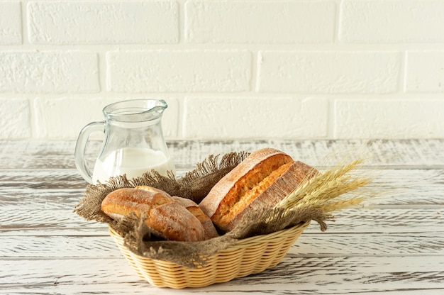 Composizione di vari prodotti da forno in cesto su fondo rustico con brocca di latte. Pasticceria fresca fatta in casa.