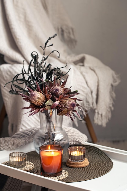 Composizione domestica con un bouquet di fiori di protea e candele