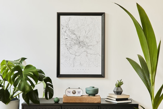 Composizione elegante degli interni del soggiorno con comò nero di design, molte piante, mappa dei poster, decorazioni ed eleganti accessori personali. Arredamento moderno per la casa.