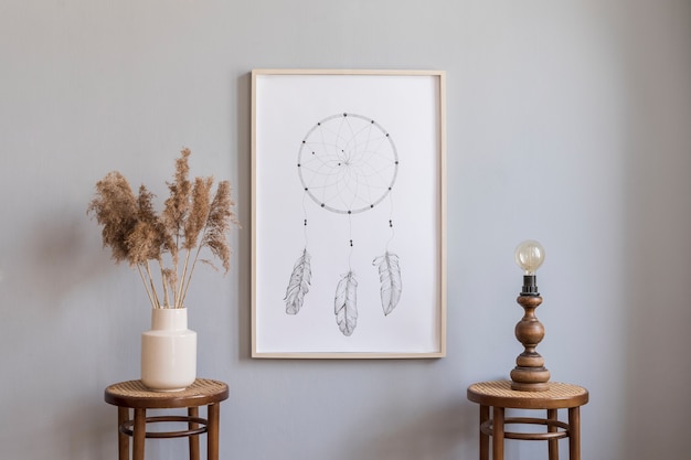 Composizione elegante di interni spaziosi e creativi con cornice per poster finta, comò e accessori. Pareti grigie e pavimento in parquet. Stile bohémien. Modello