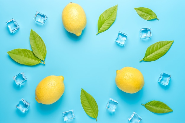 Composizione estiva creativa con limone e cubetti di ghiaccio sulla superficie blu.