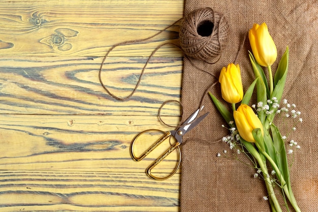 Composizione floreale Delicati tulipani gialli e forbici su un tavolo di legno closeupxDxA