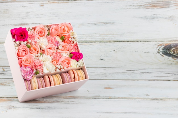 Composizione floreale di rose rosa con macarons di diversi colori