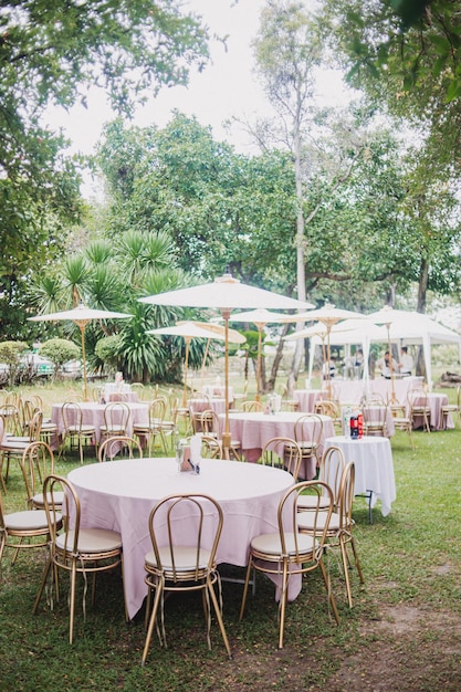 Composizione floreale per il matrimonio estivo fatto di rose e rami verdi su un tavolo da pranzo nel ristorante Vetro e piatti nel ristorante all'aperto in una giornata ventosa con effetto grana della pellicola