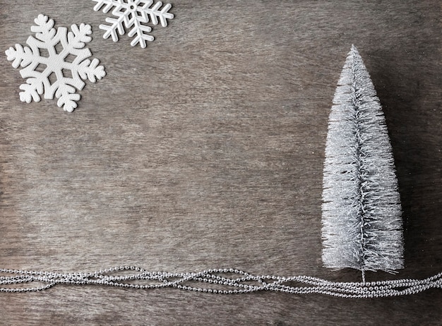 Composizione in Natale con albero di Natale d'argento e fiocchi di neve su legno.