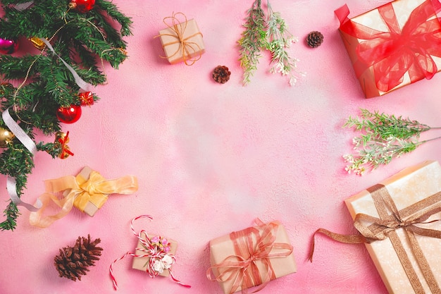 Composizione in Natale con decorazioni e confezione regalo con fiocchi su sfondo rosa pastello. inverno, concetto di nuovo anno. Appartamento laico, vista dall'alto, copia dello spazio.