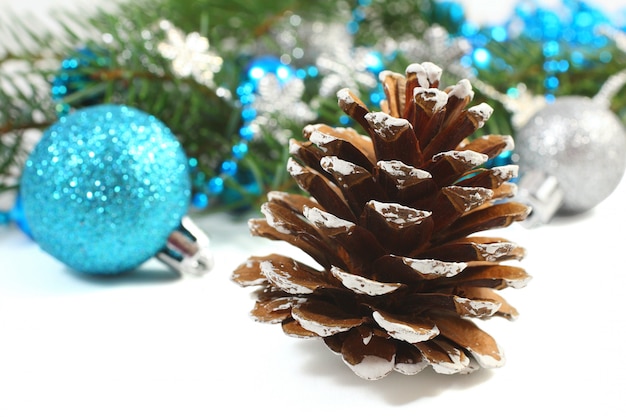 Composizione in natale con il pinecone e la sfera blu sopra bianco