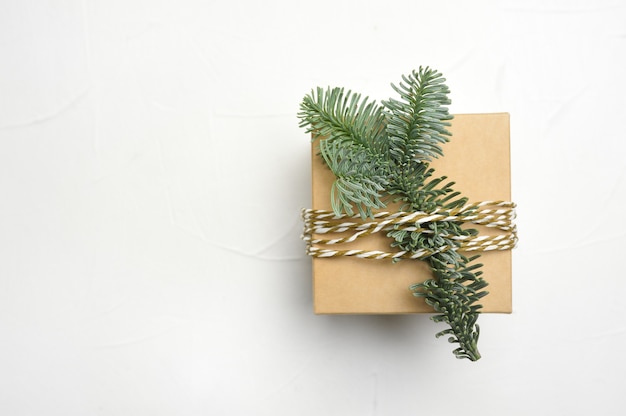 Composizione in natale con rami di abete verde e confezione regalo kraft su fondo di legno bianco con copyspace.