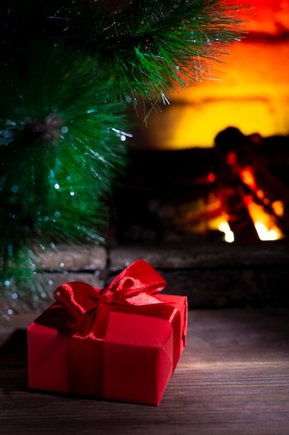 Composizione in natale, regalo sotto l'albero vicino ad un camino bruciante, primo piano