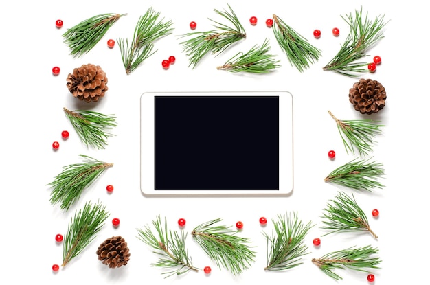 Composizione in Natale su sfondo bianco. Schermo tablet vuoto per testo o saluti. Lay piatto, copia spazio.