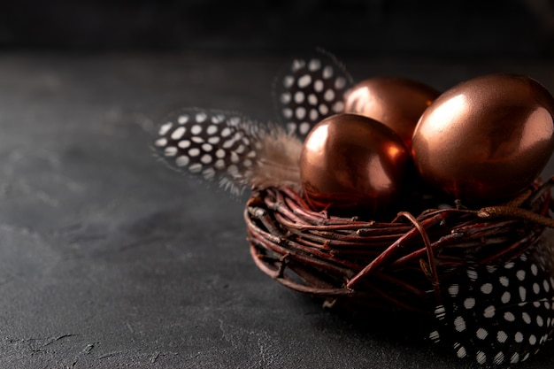 Composizione in Pasqua con le uova in un nido e piuma su fondo scuro. Biglietto di auguri di Pasqua