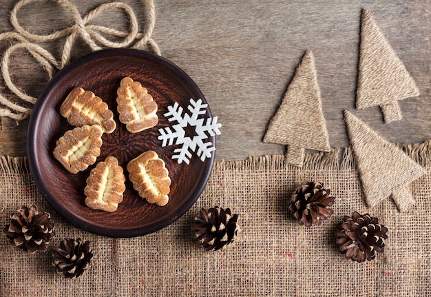 Composizione invernale rustica con biscotti di pasta frolla su un piatto e pigne