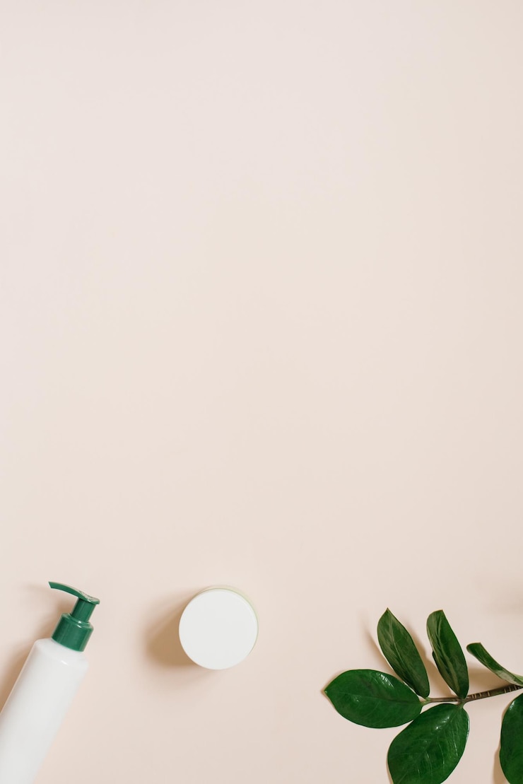Foto composizione minima con cosmetici per la cura della pelle e verde su sfondo beige pastello spazio di copia piatto